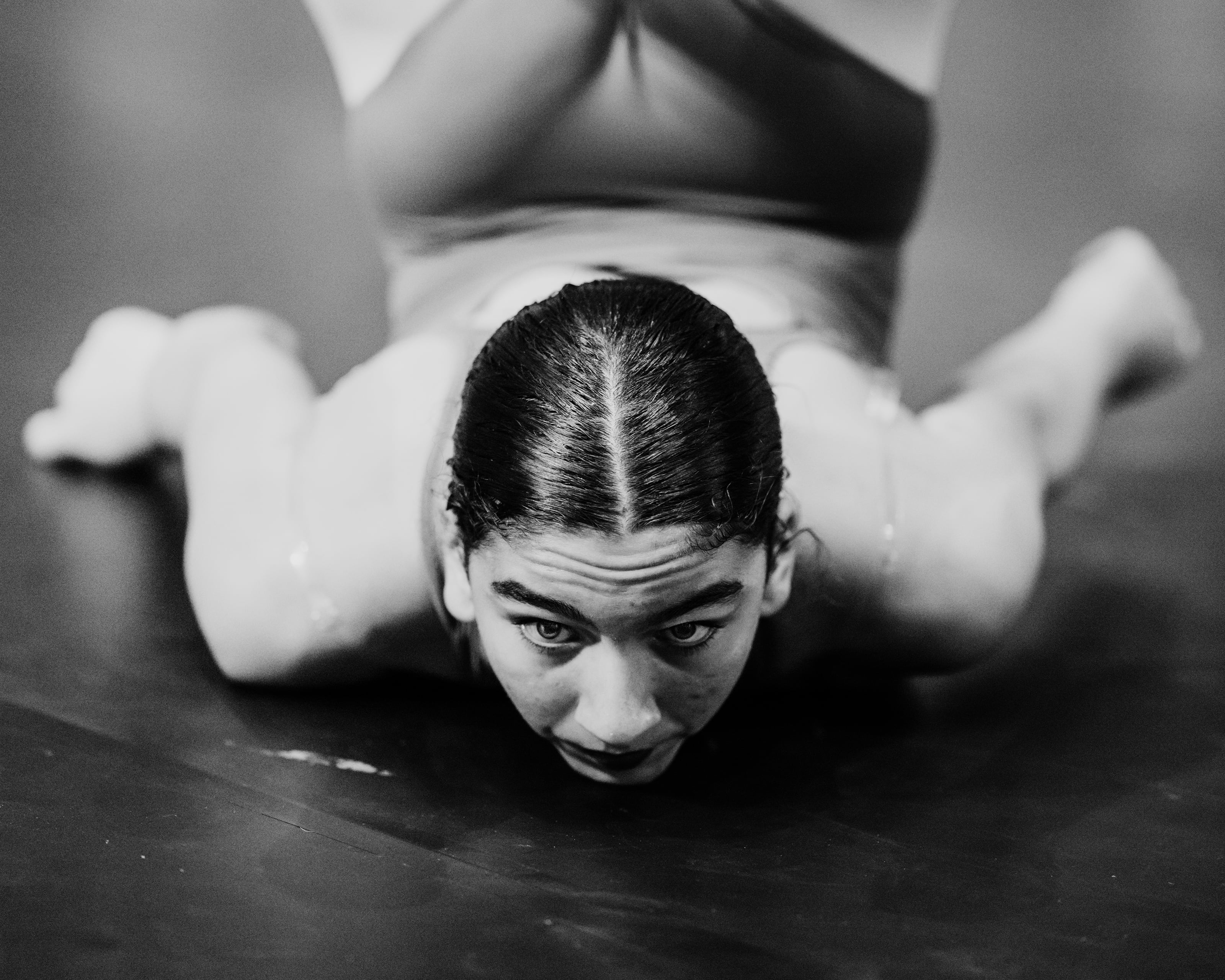 Dancer lies on the floor with bent legs, looking forward.